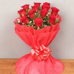 Bunch of 12 red roses in red paper packing